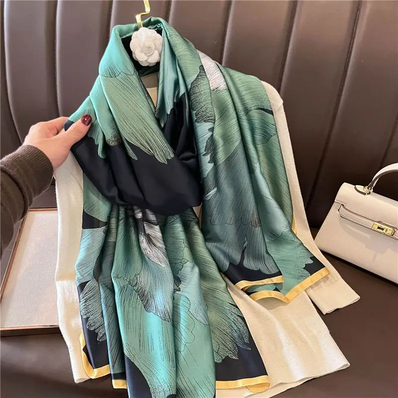 Grün gemusterter Schal mit Blumen, locker über Sofa und Pullover drapiert
