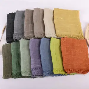 Viele einfarbige Schals mit Knitterstruktur und Fransenkante in verschiedenen Farben nebeneinander gefaltet