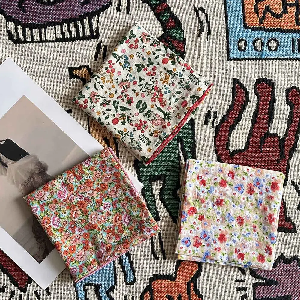 Drei gefaltete Tücher mit Blumenmuster in Rot, Grün und Blau auf Stoff