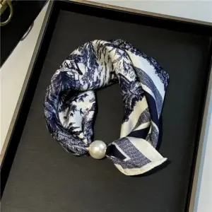 Bedrucktes Halstuch in Blau und Weiß mit Perle, locker in einer schwarzen Schachtel gelegt