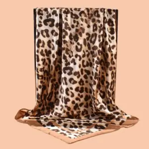 Quadratisches Satintuch mit Leopardenmuster in Beige und Braun, drapiert vor Pfirsichhintergrund