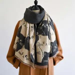 00-9 Grau-cremefarbener Schal mit Katzenmotiven und Fransen, auf einer Büste über einem Mantel drapiert
