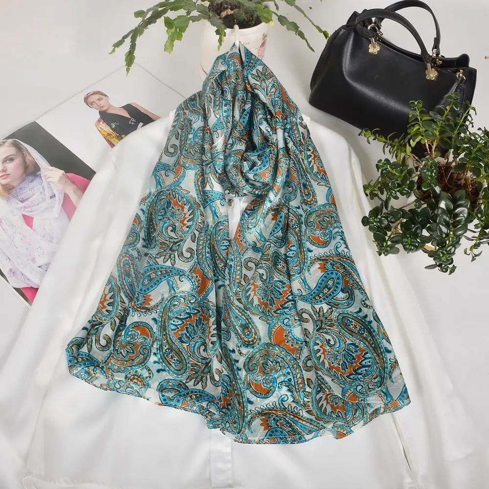 Schal mit Paisleymuster in Türkis und Orange, über weißer Bluse drapiert